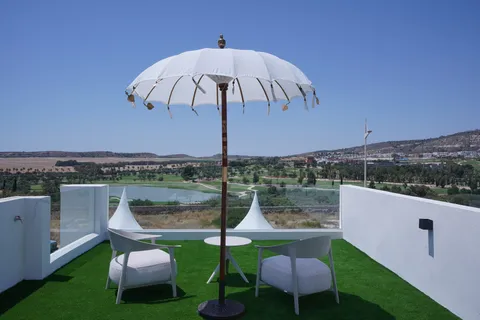 Le solarium sur le toit de la villa témoin, avec gazon synthétique, deux fauteuils, parasol et garde-corps vitré, et le golf et son lac derrière